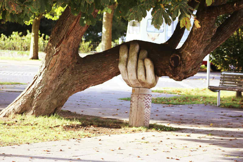 Hölzerne Hand stützt überhängenden Ast